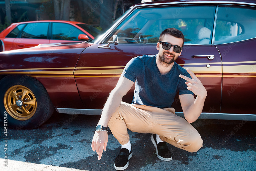 Φωτογραφία handsome bearded man in front of old school muscle car,outdoor portrait of styli