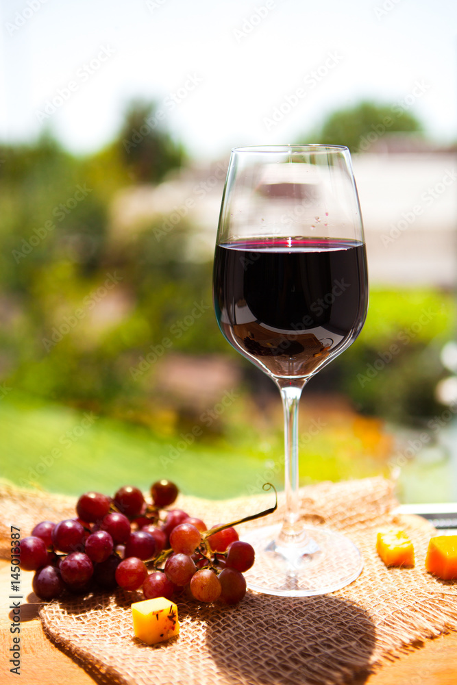 Grape, cheese,  with a one glass of red  wine on green background
