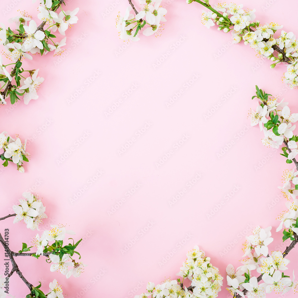Spring time background. Frame of spring white flowers on pink background. Flat lay, top view.