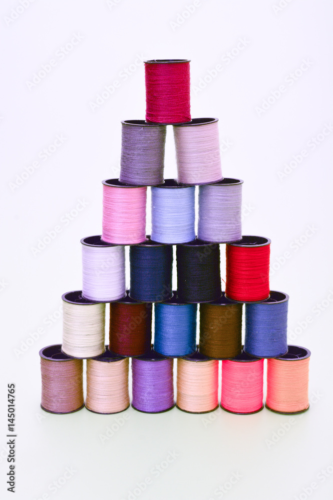 Coils with multi-colored threads made up in a pyramid on a white background Coils with multi-colored threads made up in a pyramid on a white background