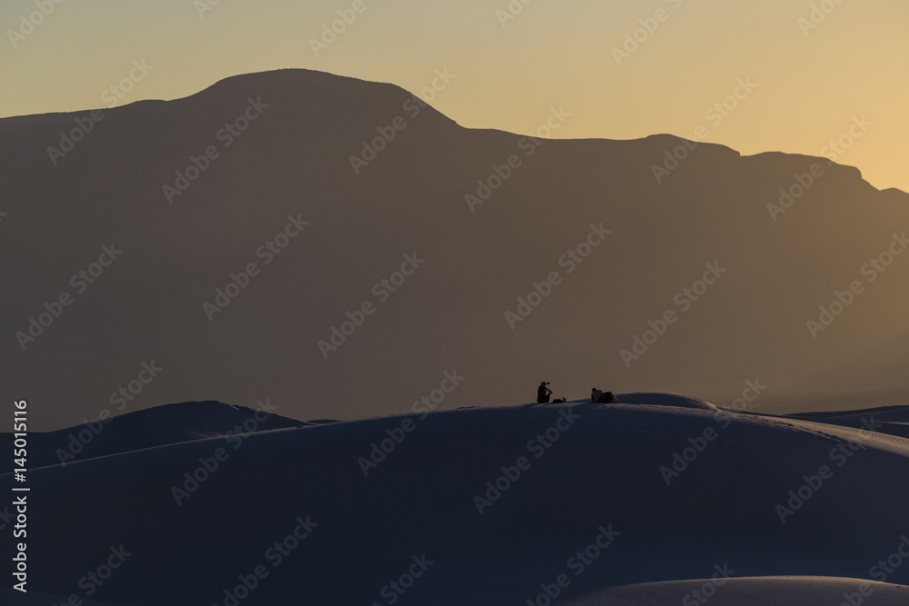 Hikers on sand dunes watching the sunset