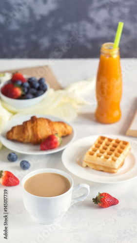 Morning Coffee mug with croissant, viennese wafer, juice and fresh berries, cozy and tasty breakfast. Selective focuse