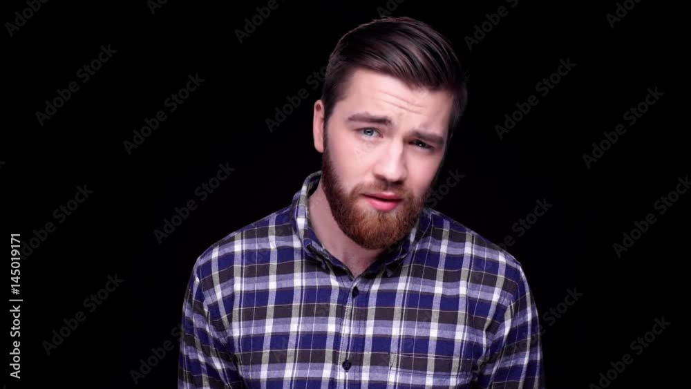 Upset disappointed bearded man looking at camera and nodding isolated over black Upset disappointed bearded man looking at camera and nodding isolated over black