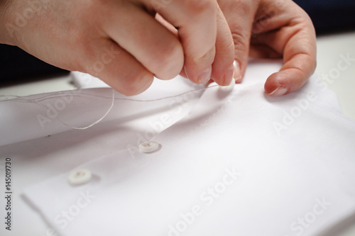 close-up picture of the hands of a seamstress at work with white fabric