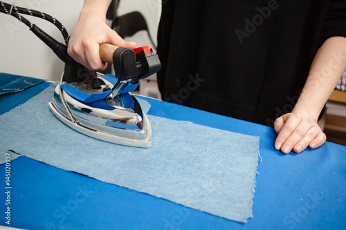 Tailor ironing the jeans fabric close up picture