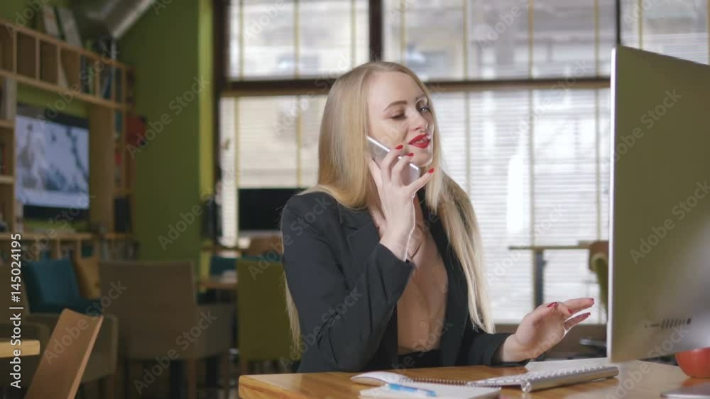 Woman working on computer at office while talking on phone Woman working on computer at office while talking on phone