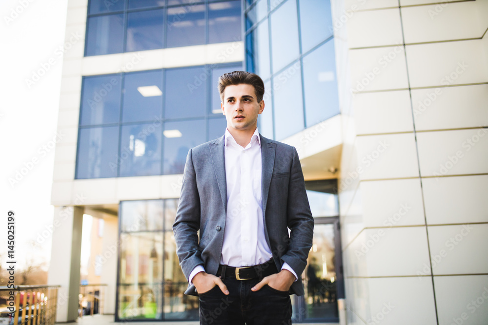 Elegant handsome young businessman while walking in front of office building Elegant handsome young businessman while walking in front of office building