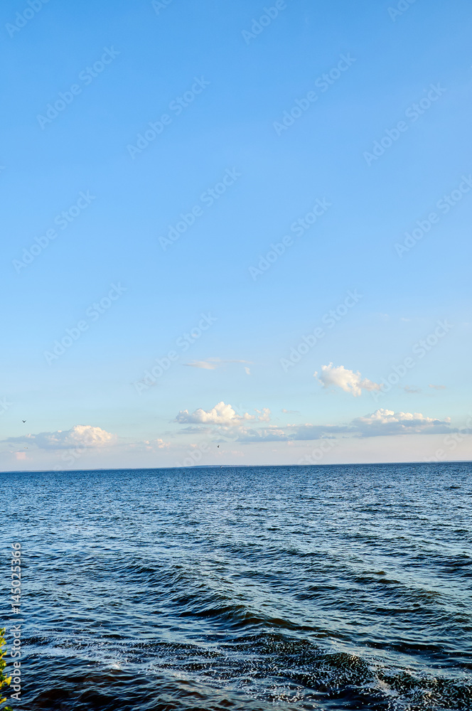 Fototapeta premium Beautiful sea, river, lake, reservoir. Ukraine, Dnepropetrovsk region, Nikopol city. Natural panorama in the rays of the setting, the rising sun. A magnificent blue sky with neat clouds. 
