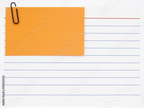 Blue lined index card with orange notecard attached with red paperclip. Isolated.