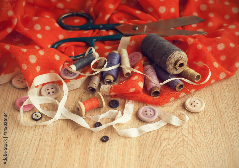 Old scissors, spools of thread, buttons and ribbons in vintage style.