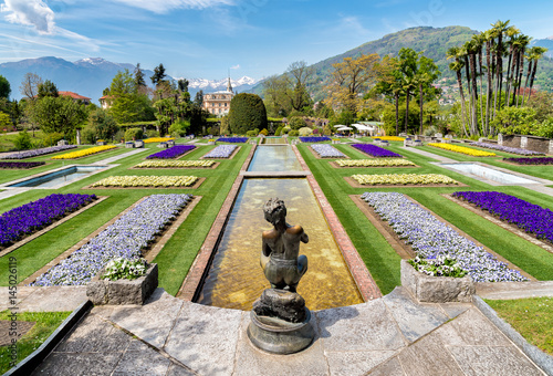 Botanical Gardens of Villa Taranto with bronze statue The Fisher in front, Pallanza, Verbania, Italy.
