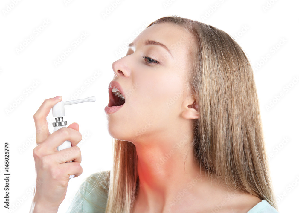 Sick young woman using throat spray on white background Sick young woman using throat spray on white background