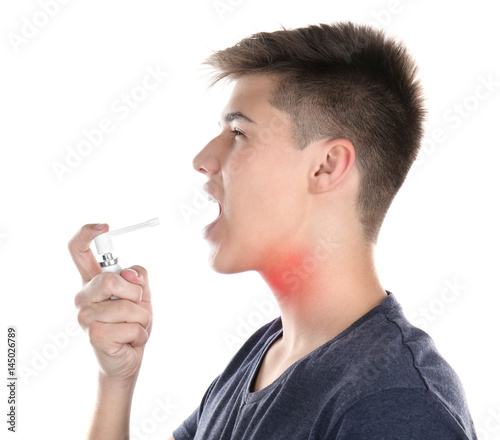 Allergies and sore throat concept. Sick young man using spray on white background