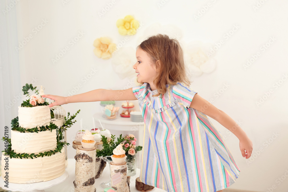 Cute girl near table with sweets served for party Cute girl near table with sweets served for party