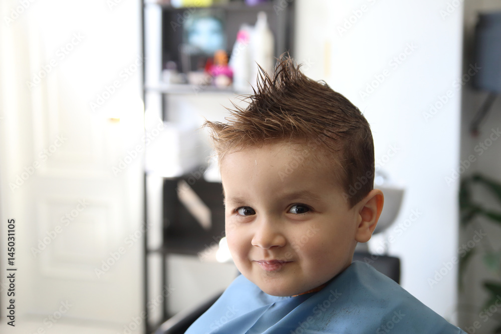 happy little kid with a modern hairstyle in the barbershop happy little kid with a modern hairstyle in the barbershop