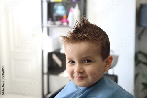 happy little kid with a modern hairstyle in the barbershop