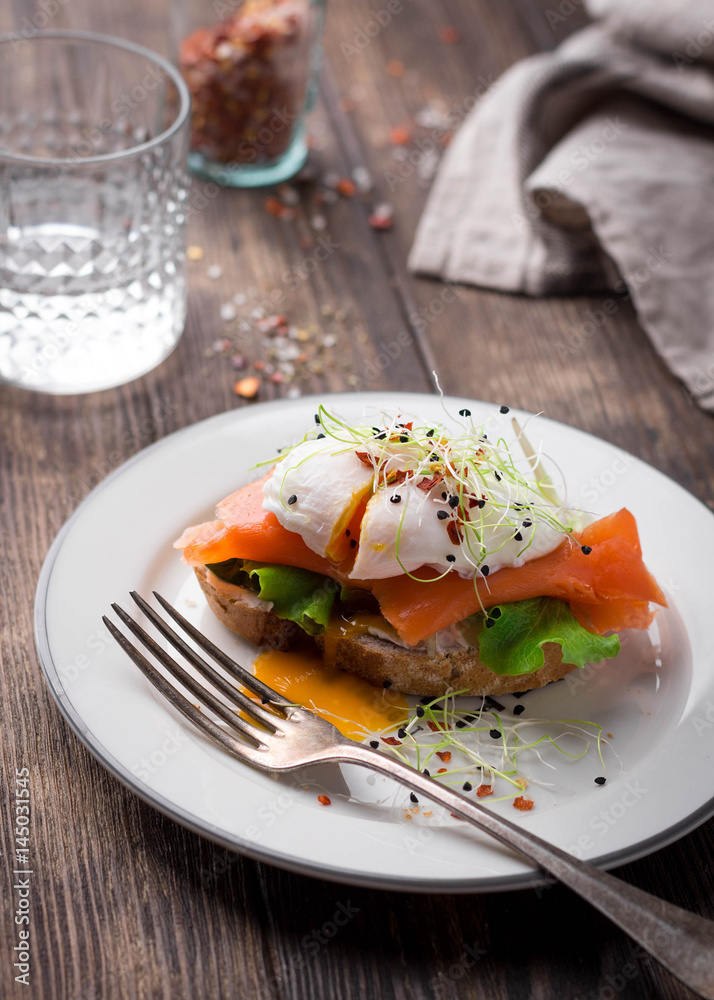 Delicious toast with salad, salted salmon and poached egg on rustic background; Delicious toast with salad, salted salmon and poached egg on rustic background;
