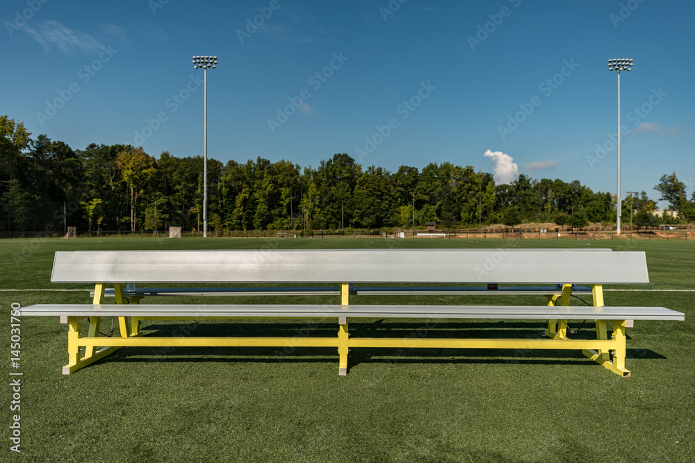 Empty aluminum bench team sports background on a green turf field Empty aluminum bench team sports background on a green turf field