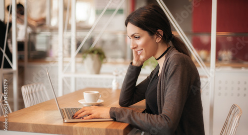 Smiling young woman drinking a coffee and surfing on internet photo