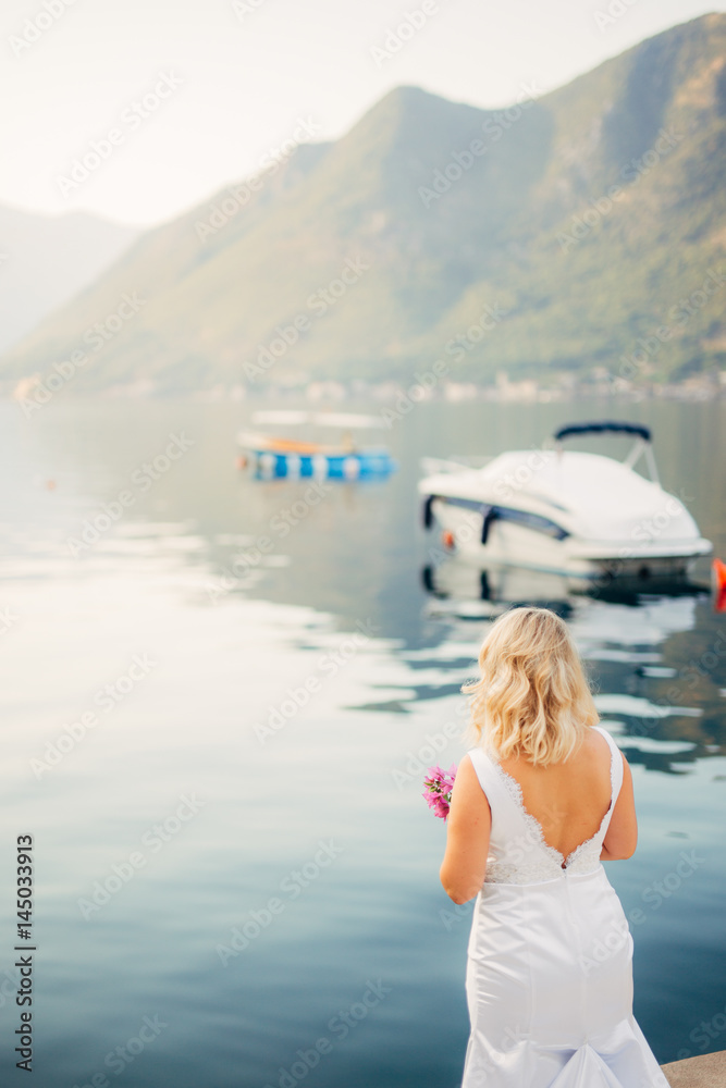 A girl on the shore looks at a yacht in the sea in Montenegro