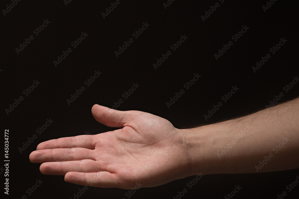 Right hand Extended male arm with open palm on a black background