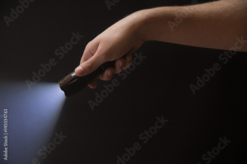 The flashlight in the man's hand from the right upper corner , isolated on black background