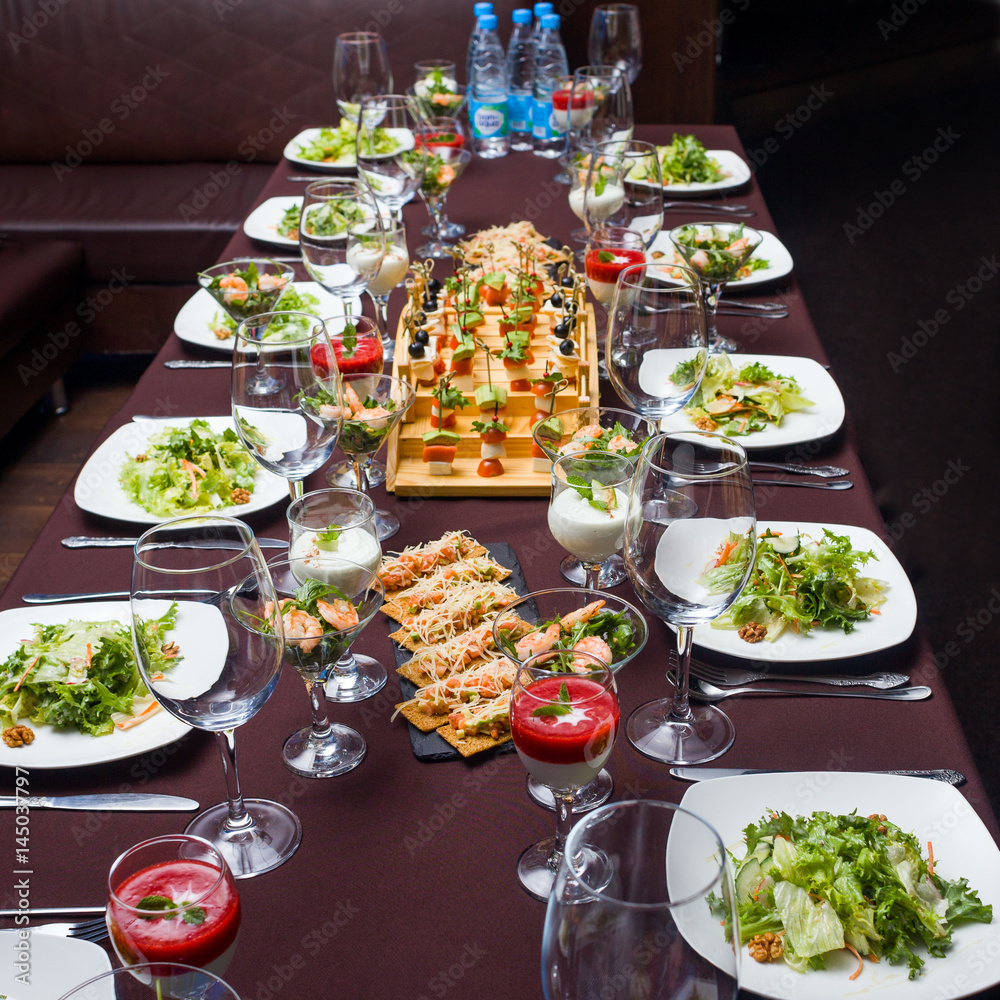 the table is laid for celebration,  there are glasses and salad and snack