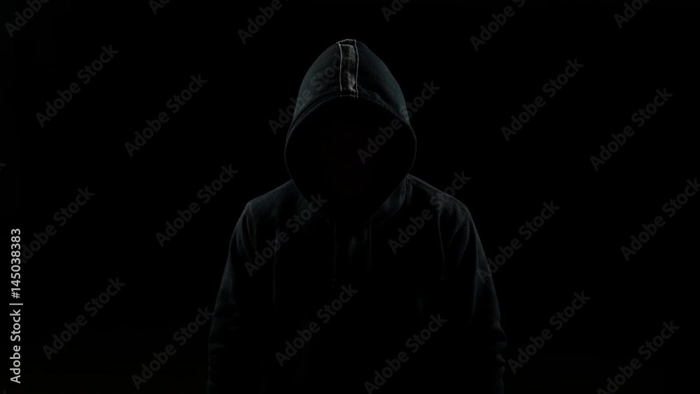 Portrait of invisible man with a hood nodding his head indoor on black background Portrait of invisible man with a hood nodding his head indoor on black background