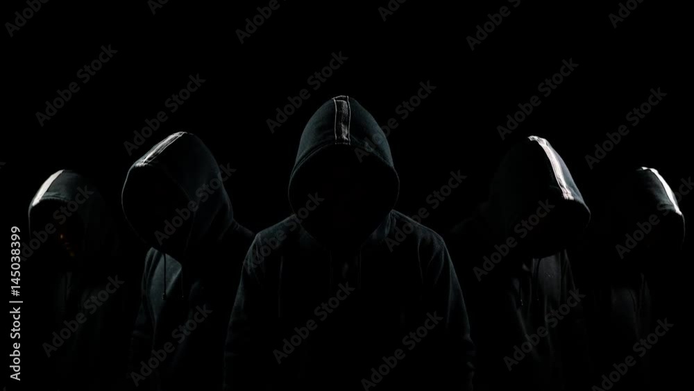 Five mysterious hooded men standing in the dark