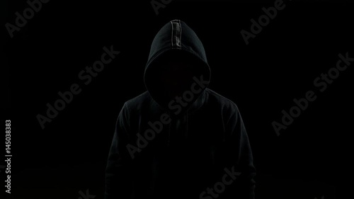 Portrait of invisible man with a hood nodding his head indoor on black background