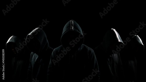 Five mysterious hooded men standing in the dark