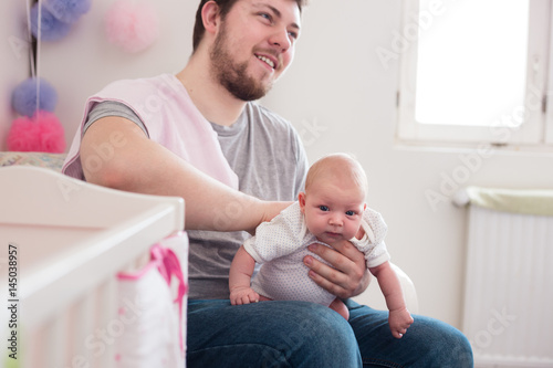 Young father burping his newborn daughter, holding her affectionately. Lifestyle shoot with natural light. photo