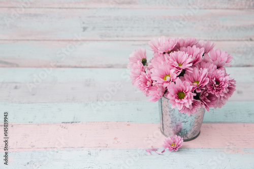 Flowers in bucket over wooden background. Shabby chic stile. Space for text