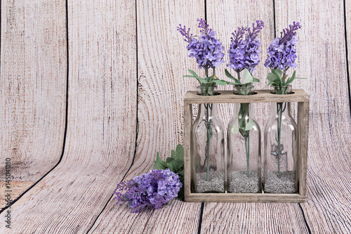 Fototapeta Naklejka Na Ścianę i Meble -  Flores de lavanda en botellas de cristal y soporte de madera.