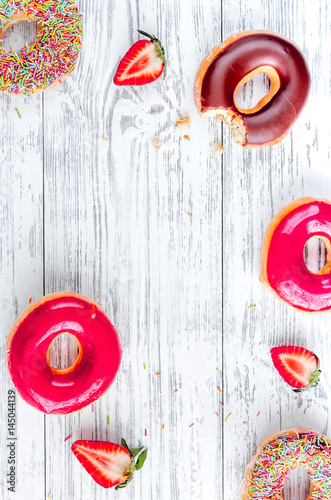 sweet colorful donuts with topping on wooden desk background top view mock-up