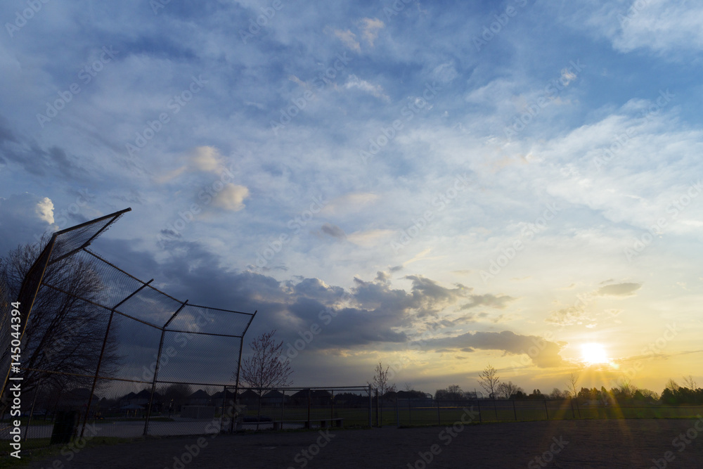 Silhouette of baseball diamond fence at dawn, beautiful sunrise sky with space for text Silhouette of baseball diamond fence at dawn, beautiful sunrise sky with space for text