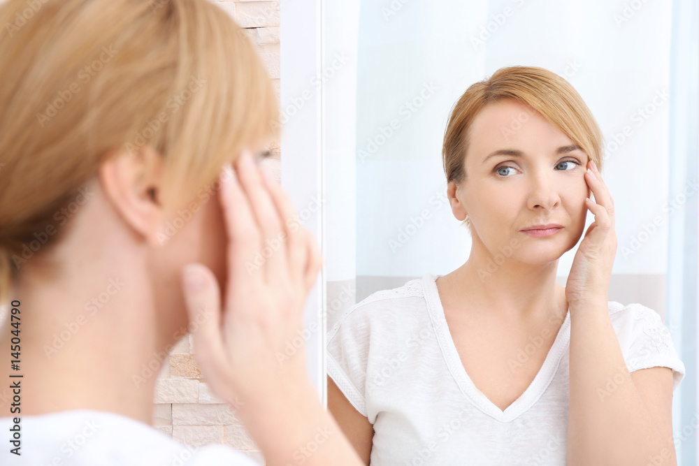 Happy senior woman applying anti-aging cream near mirror Happy senior woman applying anti-aging cream near mirror