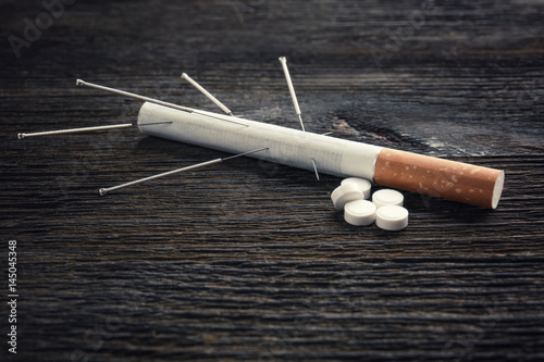 Cigarette with needles and pills on table