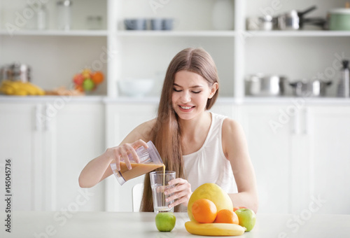 Young woman pouring fresh j...