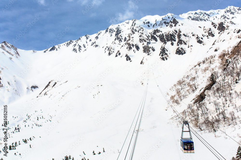 Cable car on snow covered mounytain under blue sky