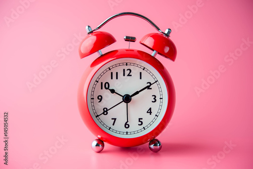 close up of a vintage red bell clock on pink background