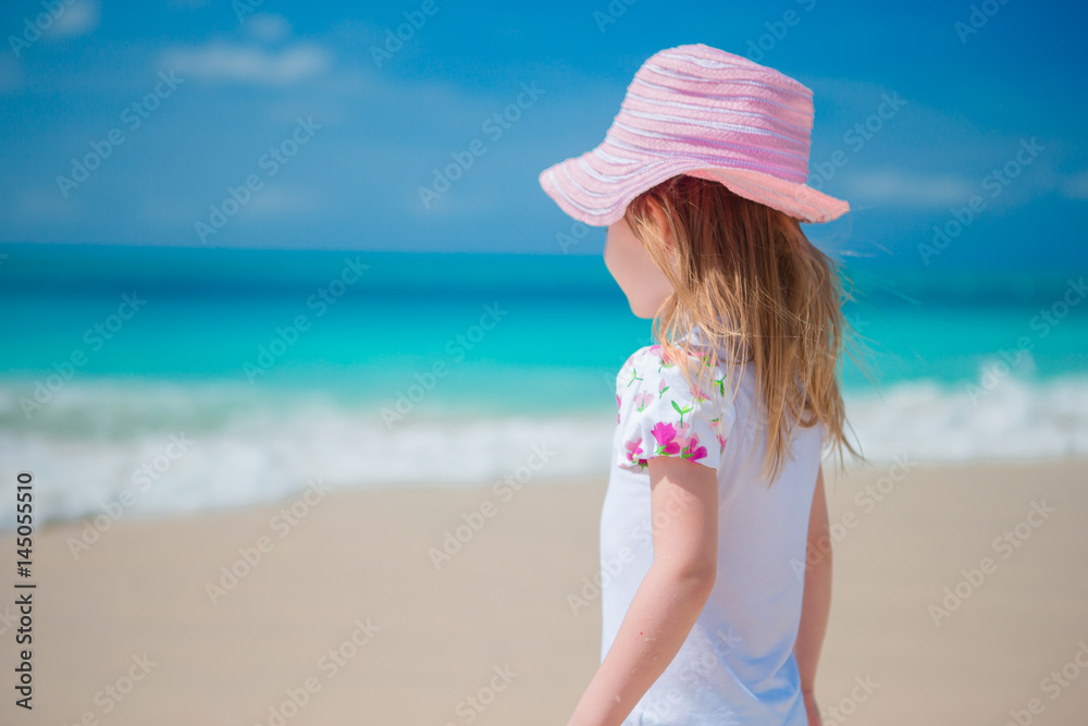 Adorable little girl walking along white sand Caribbean beach Adorable little girl walking along white sand Caribbean beach
