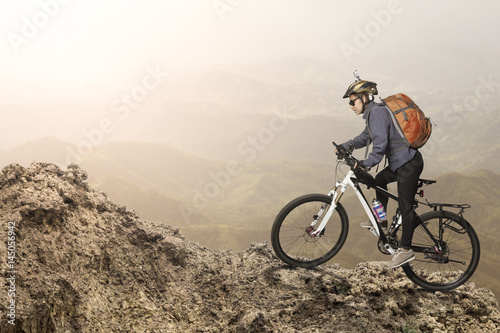 Female biker riding on bicycle in mountains on sunset