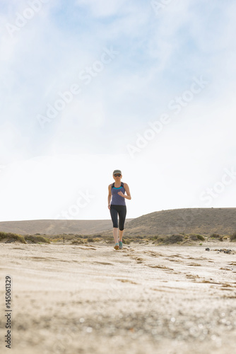 Athletic Lady Running in the Desert with Blue Sky Background