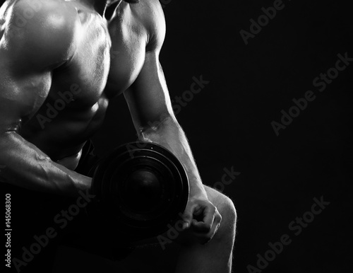 Monochrome cropped close up of a shirtless male athlete with stunning hot sexy strong body lifting dumbbells copyspace biceps chest workout training exercising shape toning bodybuilder gym.