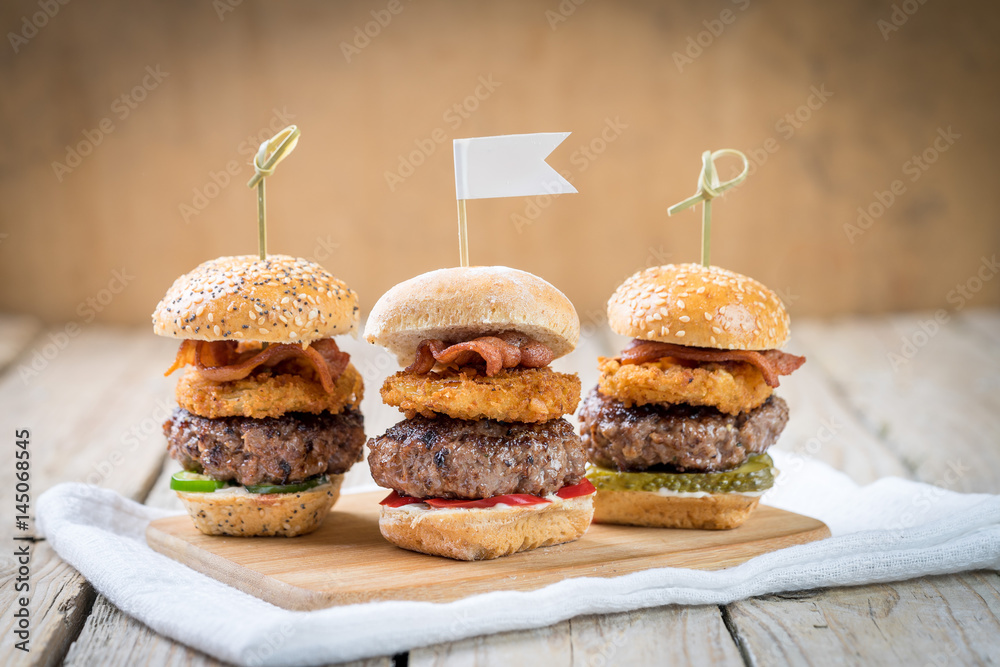 Small beef sliders grilled burgers onion rings little buns bacon served as appetisers for sharing