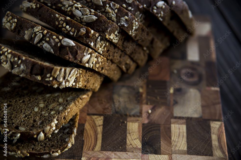 Black bread with seeds and sesame seeds on a board of wooden logs