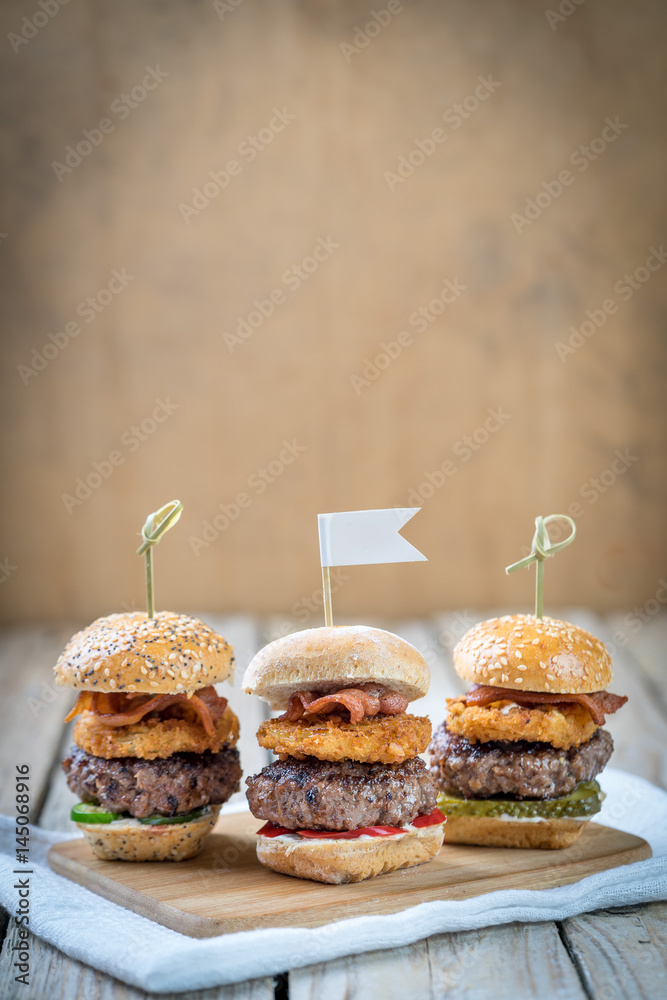 Small beef sliders grilled burgers onion rings little buns bacon served as appetisers for sharing