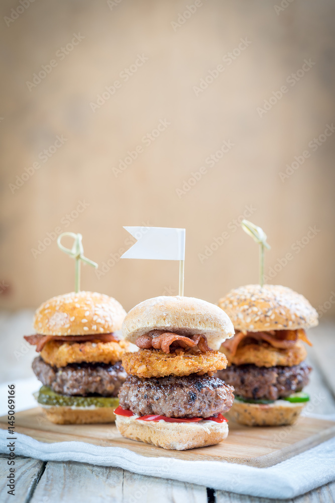 Small beef sliders grilled burgers onion rings little buns bacon served as appetisers for sharing