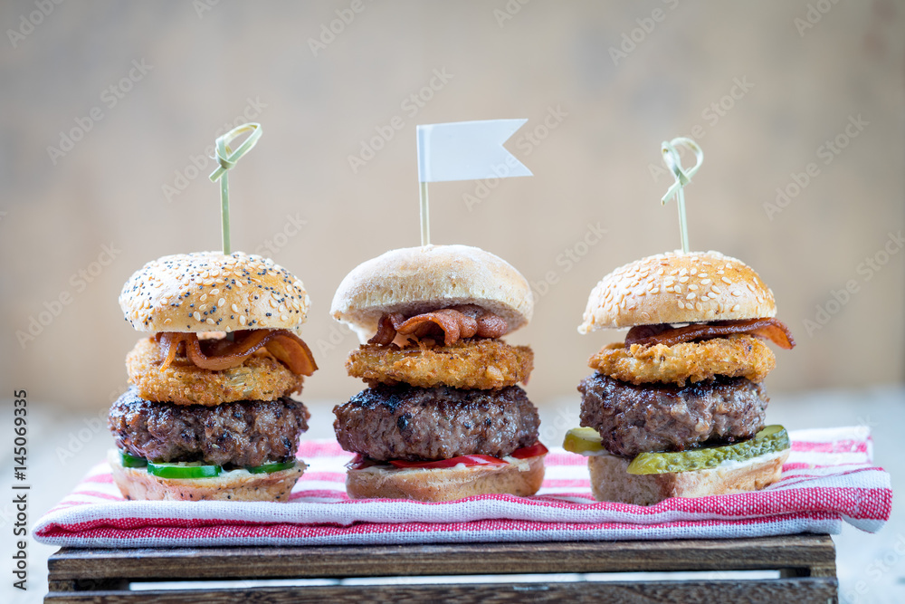 Small beef sliders grilled burgers onion rings little buns bacon served as appetisers for sharing